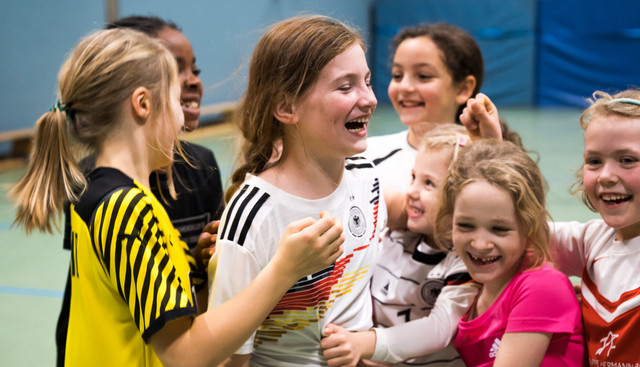 Kinder umarmen sich, freuen sich und haben sichtlich spaß in einer Turnhalle